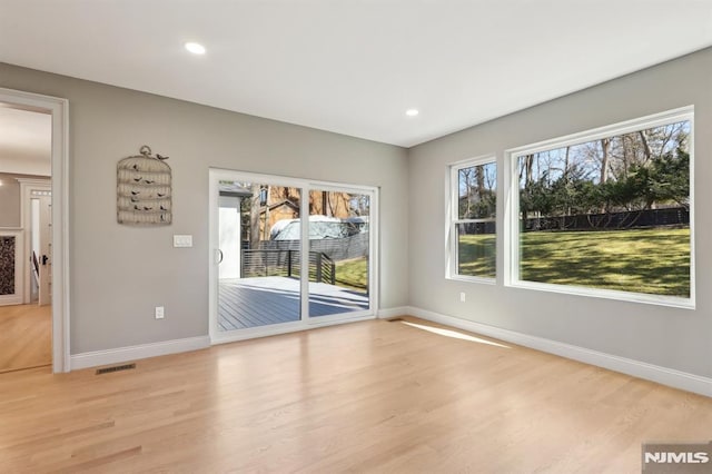 spare room with light wood finished floors, visible vents, and plenty of natural light