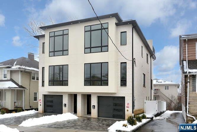 modern home featuring an attached garage, stucco siding, and brick siding