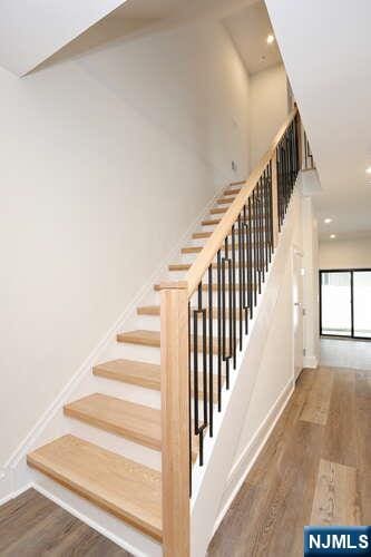 staircase with baseboards, wood finished floors, and recessed lighting