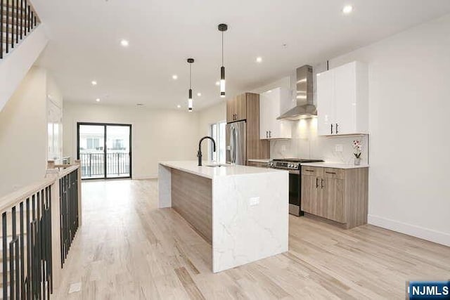 kitchen featuring wall chimney exhaust hood, modern cabinets, stainless steel appliances, and decorative backsplash