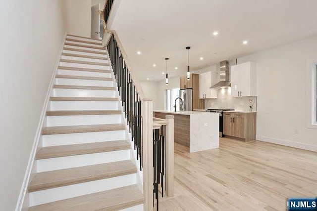 stairs with baseboards, wood finished floors, and recessed lighting