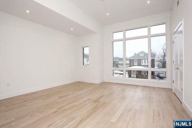 spare room featuring light wood-style floors, recessed lighting, and baseboards