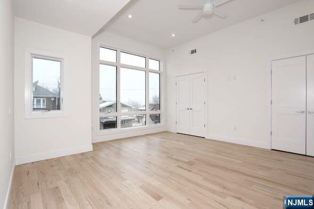 empty room featuring light wood-style floors, baseboards, visible vents, and ceiling fan