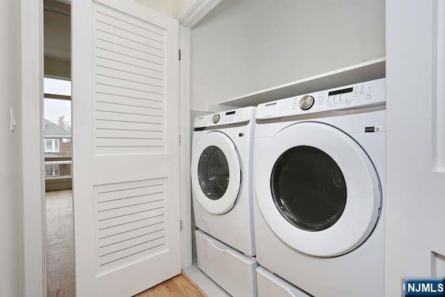 laundry area with laundry area, independent washer and dryer, and light wood-style flooring