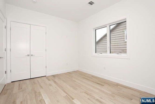 unfurnished bedroom featuring a closet, light wood-type flooring, visible vents, and baseboards