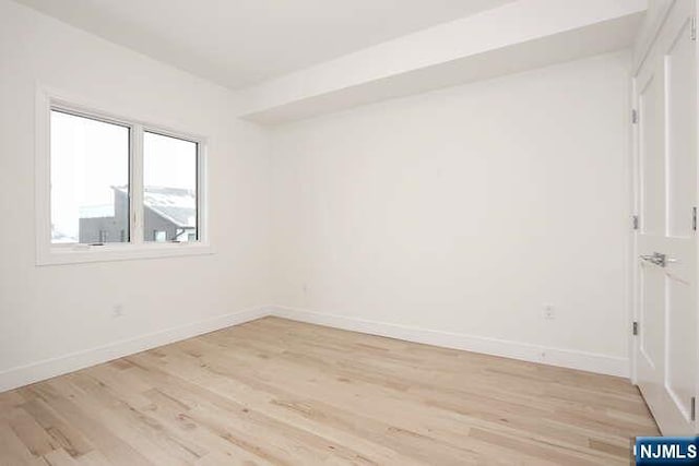 empty room with light wood-style flooring and baseboards