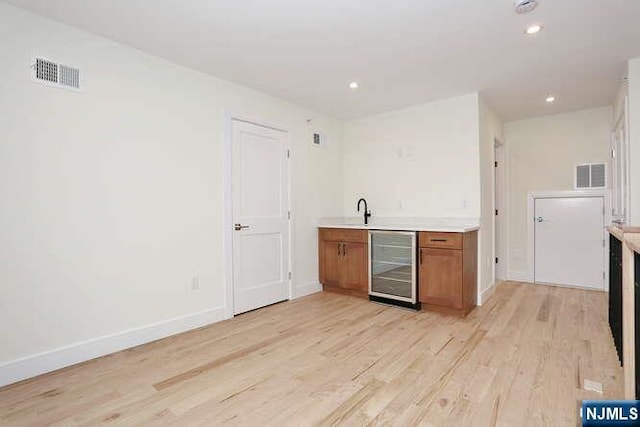 kitchen featuring beverage cooler, light countertops, visible vents, and brown cabinets