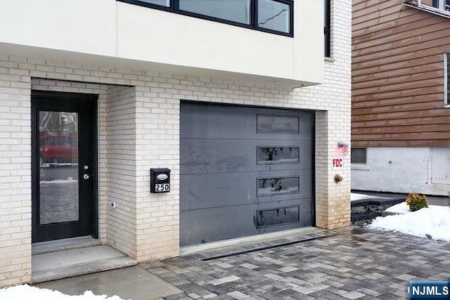 property entrance with an attached garage and brick siding