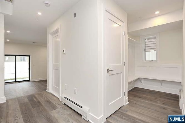 corridor featuring a baseboard radiator, recessed lighting, and wood finished floors