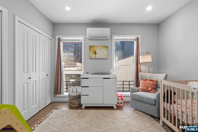 bedroom featuring light wood-type flooring, a closet, a wall unit AC, and recessed lighting