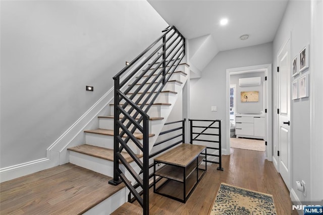 stairs with baseboards, wood finished floors, and a wall mounted air conditioner