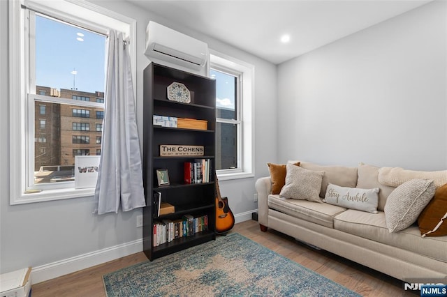 living area featuring a wall mounted air conditioner, wood finished floors, and baseboards