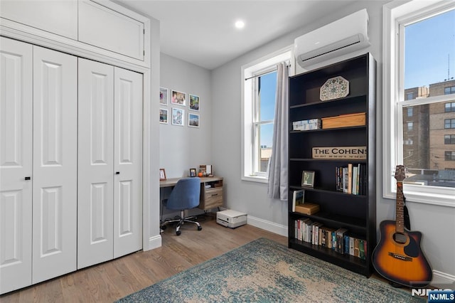 office area with wood finished floors, baseboards, and a wall mounted AC