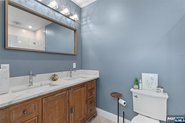 bathroom with double vanity, baseboards, toilet, and a sink