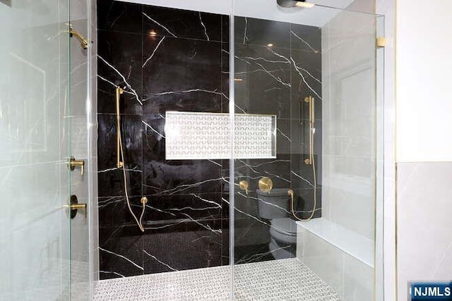 bathroom featuring toilet and a marble finish shower