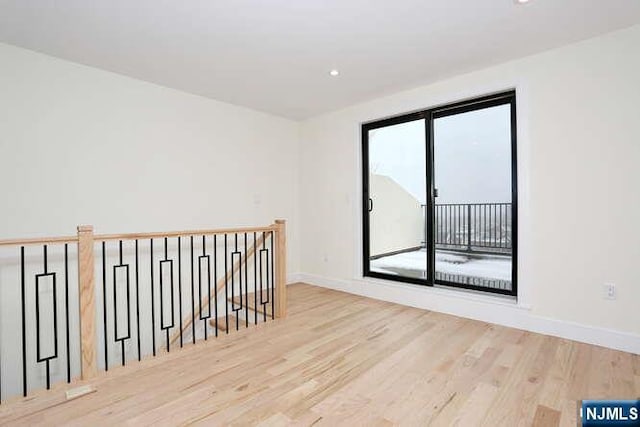 spare room featuring baseboards, wood finished floors, and recessed lighting