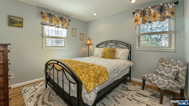 bedroom with baseboards, multiple windows, and wood finished floors