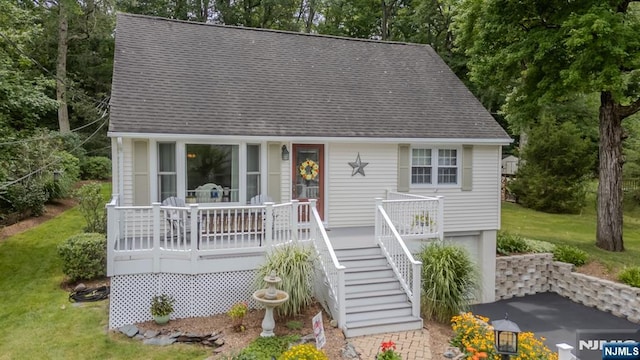 view of front facade featuring a front yard, stairway, an attached garage, a shingled roof, and aphalt driveway