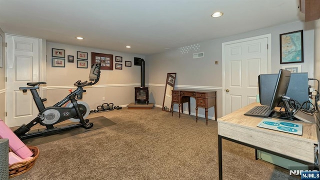 exercise room with visible vents, baseboards, a wood stove, recessed lighting, and carpet flooring