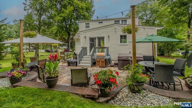 back of house featuring a patio, outdoor dining area, a lawn, and a hot tub