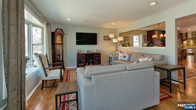 living room with recessed lighting, baseboards, an inviting chandelier, and wood finished floors