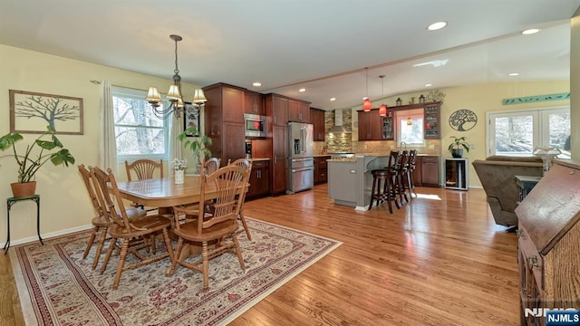 dining space featuring plenty of natural light, vaulted ceiling, and light wood finished floors