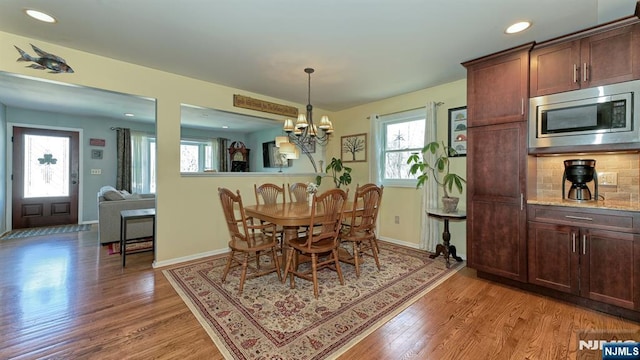 dining room with light wood finished floors, a chandelier, recessed lighting, and baseboards