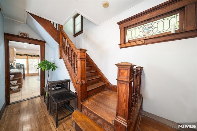 stairway featuring baseboards, ornamental molding, and hardwood / wood-style floors