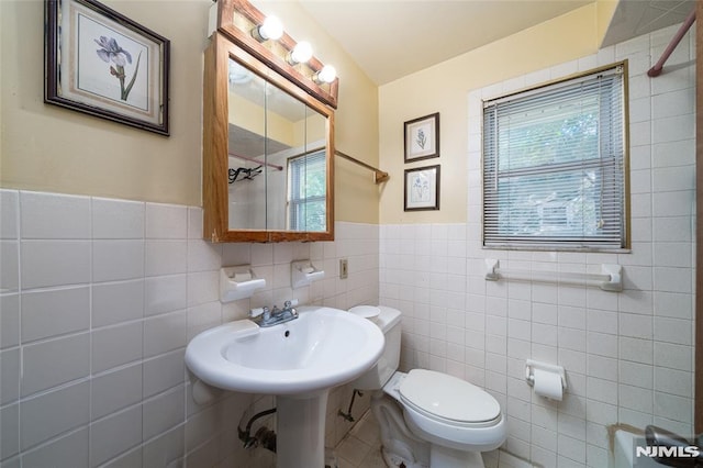 bathroom featuring a wainscoted wall, toilet, and tile walls