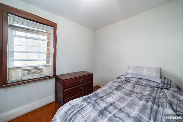 bedroom featuring cooling unit, wood finished floors, and baseboards