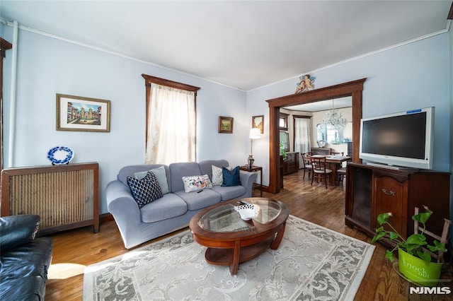 living room with a chandelier, wood finished floors, and crown molding