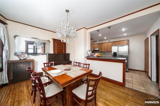 dining space with baseboards, ornamental molding, light wood-type flooring, a chandelier, and recessed lighting