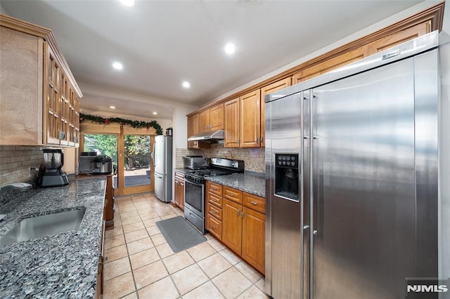 kitchen featuring decorative backsplash, stainless steel appliances, under cabinet range hood, a sink, and light tile patterned flooring