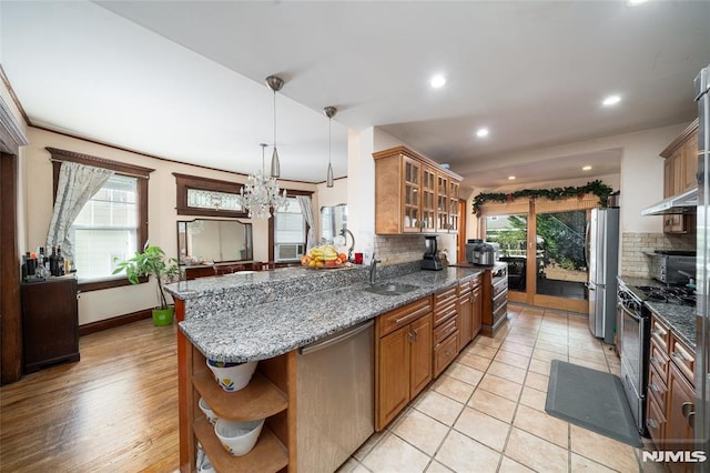 kitchen with tasteful backsplash, glass insert cabinets, appliances with stainless steel finishes, open shelves, and a sink