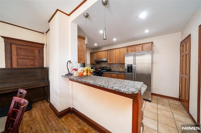 kitchen featuring a peninsula, baseboards, appliances with stainless steel finishes, brown cabinets, and tasteful backsplash