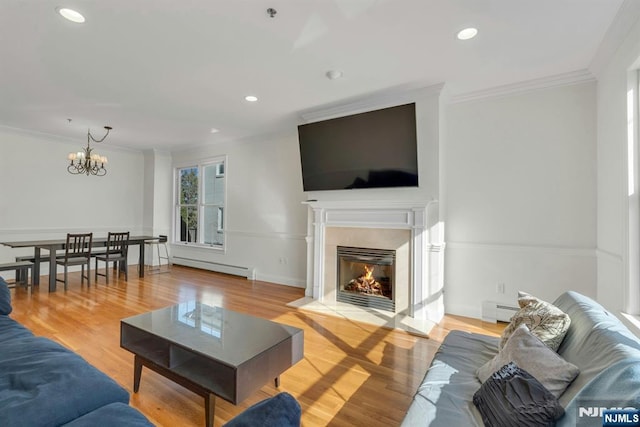 living area featuring crown molding, a baseboard radiator, a fireplace, and wood finished floors