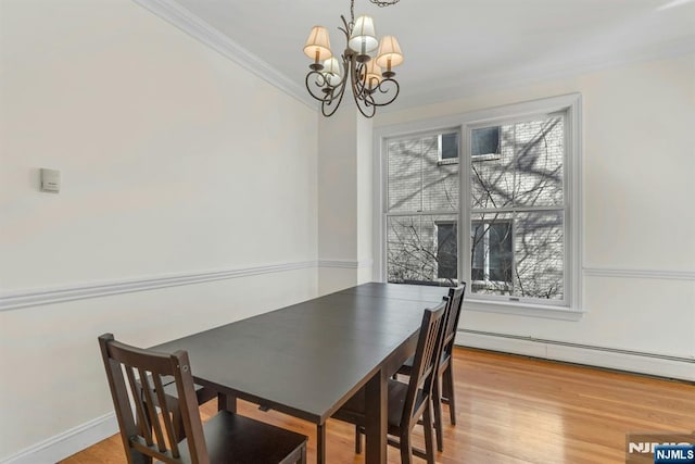 dining space featuring light wood-type flooring, an inviting chandelier, ornamental molding, and baseboard heating