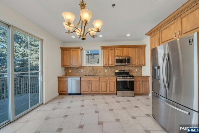 kitchen featuring stainless steel appliances, a sink, light stone counters, and tasteful backsplash