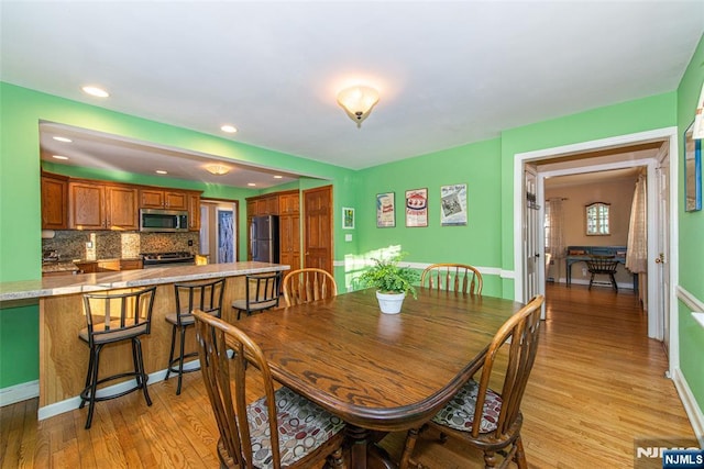 dining room featuring light wood-style flooring, baseboards, and recessed lighting