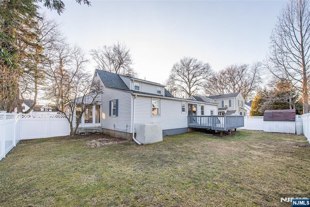 back of house featuring a wooden deck, central AC unit, a fenced backyard, an outbuilding, and a yard