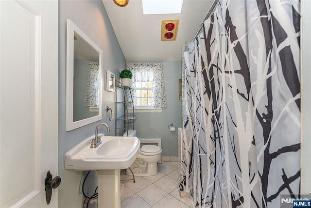 bathroom featuring toilet, a shower with shower curtain, a sink, and tile patterned floors