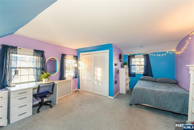 carpeted bedroom with a closet, vaulted ceiling, and baseboards