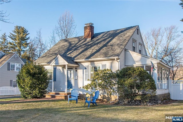 view of front of home featuring roof with shingles, fence, a chimney, and a front lawn