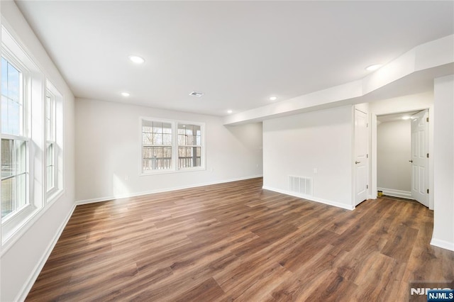 empty room with baseboards, dark wood-type flooring, visible vents, and recessed lighting