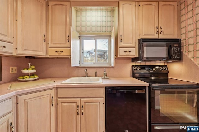 kitchen featuring black appliances, light brown cabinets, and a sink