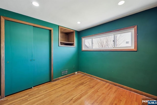 unfurnished bedroom with recessed lighting, a closet, visible vents, light wood-type flooring, and baseboards