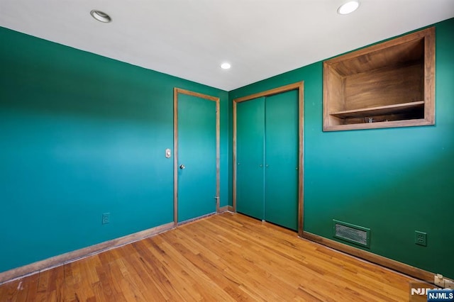 spare room with baseboards, wood finished floors, visible vents, and recessed lighting