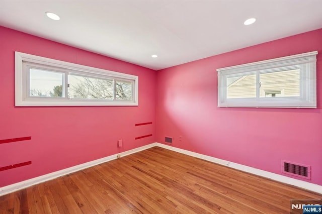 spare room featuring recessed lighting, wood finished floors, visible vents, and baseboards