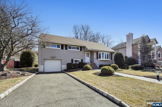 tri-level home with a garage, aphalt driveway, and a front lawn