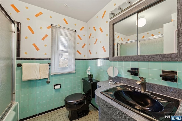 bathroom featuring toilet, a wainscoted wall, tile walls, vanity, and wallpapered walls